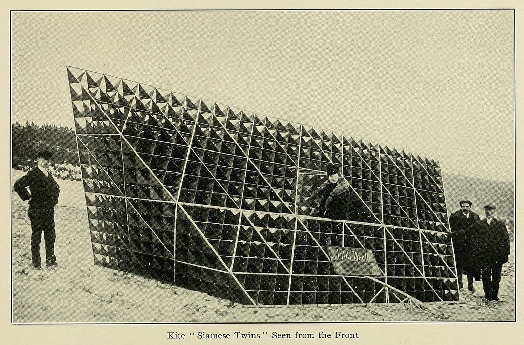 Bell's immense Siamese Twins tetrahedral kite with four men standing beside it